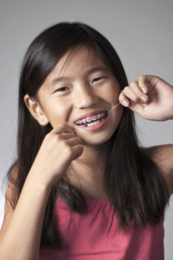 a girl with braces flossing